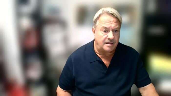 Un homme la bouche entrouverte est filmé par sa webcam avec un arrière-plan flou.