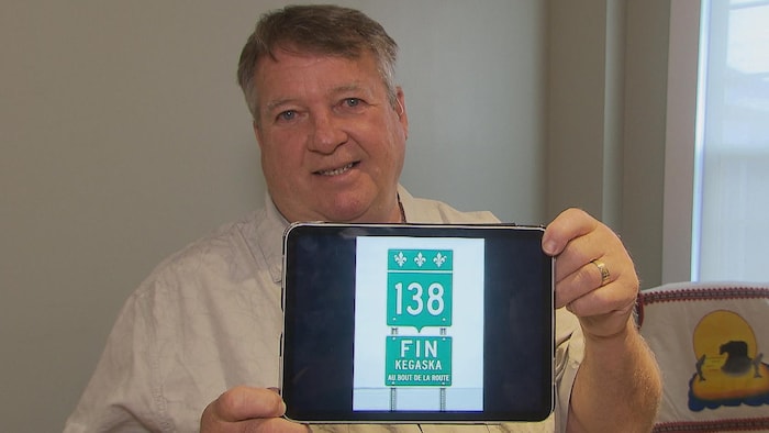 Richard Beaudry montre l'écran de sa tablette électronique, qui diffuse la photo d'un panneau routier.