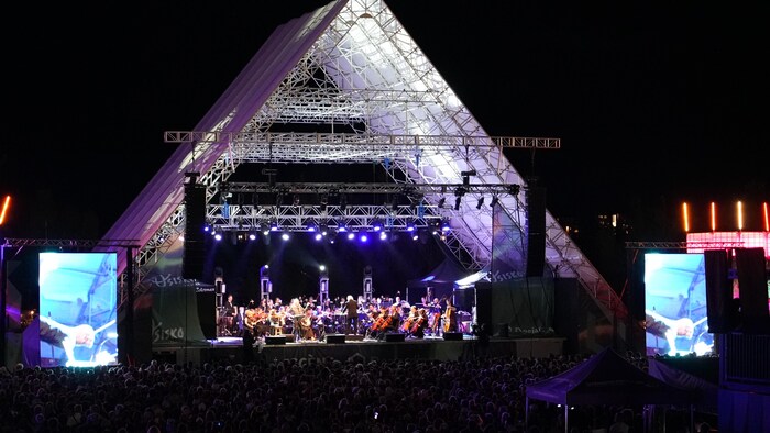 L'Orchestre symphonique régional et Richard Desjardins sur la scène d'Osisko en lumière, vus de haut.