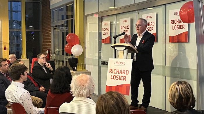 Richard Losier s'adresse à son auditoire après sa victoire. Il se trouve sur une estrade et parle au micro.