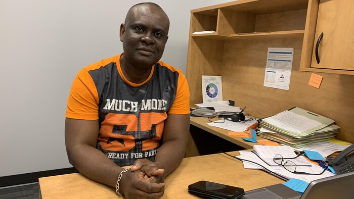Richard Makitu Dolomingo s'assied dans son bureau. Il regarde tout droit à la caméra.