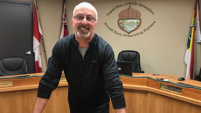 Un homme souriant dans la chambre d'un conseil municipal. 