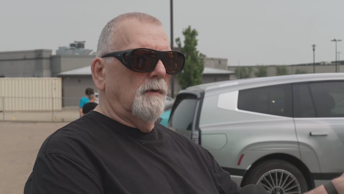 Un homme devant des automobiles.