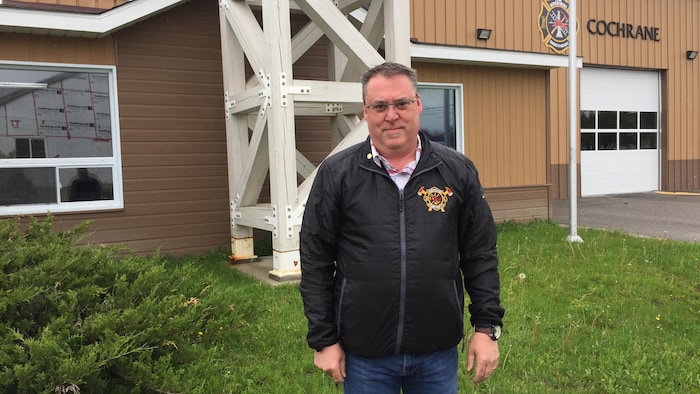 Un homme posant devant la caserne de pompiers de Cochrane.