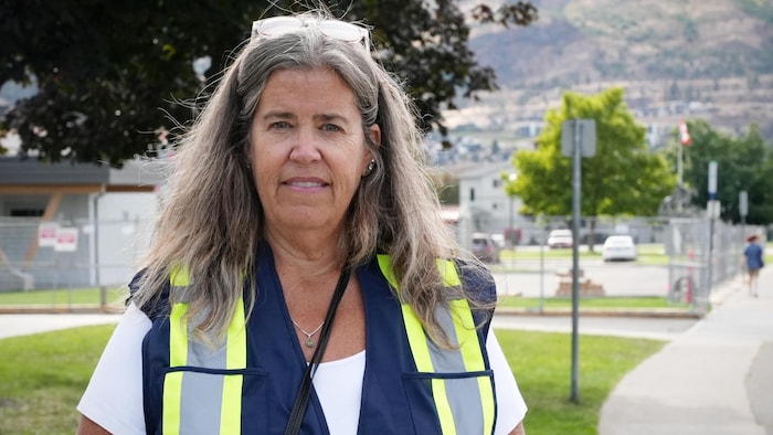 Une femme vêtue d'un dossard se tient devant une rue de Penticton, dans la vallée de l'Okanagan, le 26 septembre 2025.