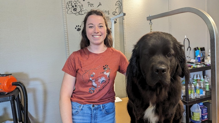 Ricky-Ann Plamondon dans son salon de toilettage avec un chien de grande taille.