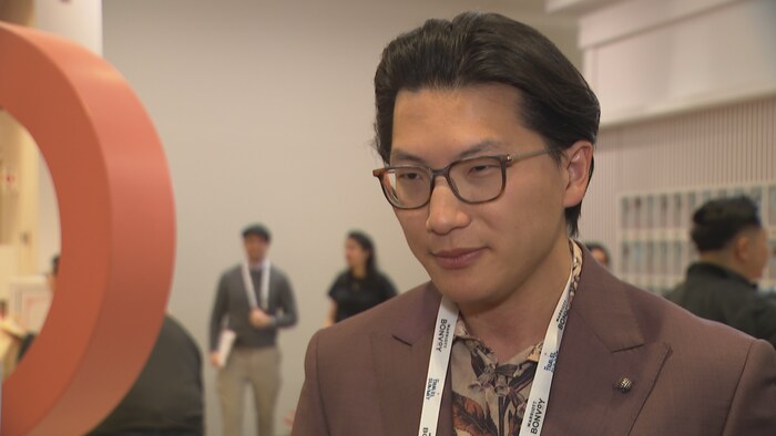 Ricky Zhang porte un veston en entrevue lors d'une conférence.