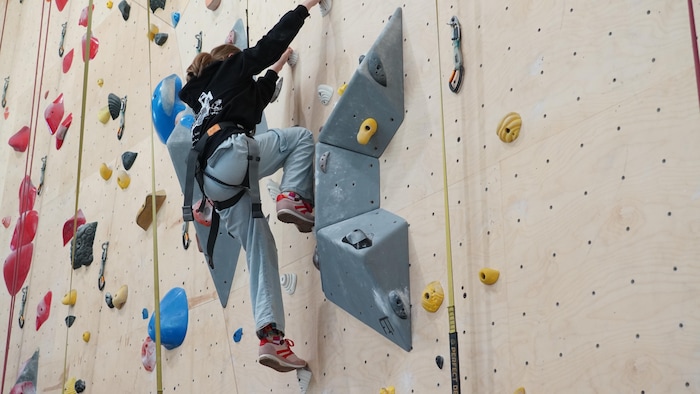 Une personne grimpe sur un mur d'escalade.