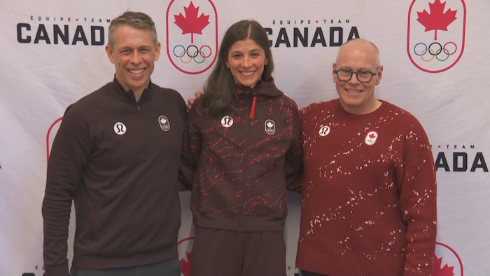 Rikki Doak, souriante, pose avec deux hommes.
