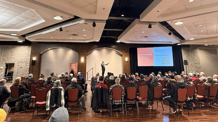 Des gens assistent à une conférence dans une salle d'hôtel.