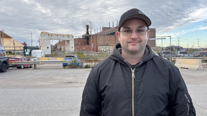 Un homme pose devant une usine.