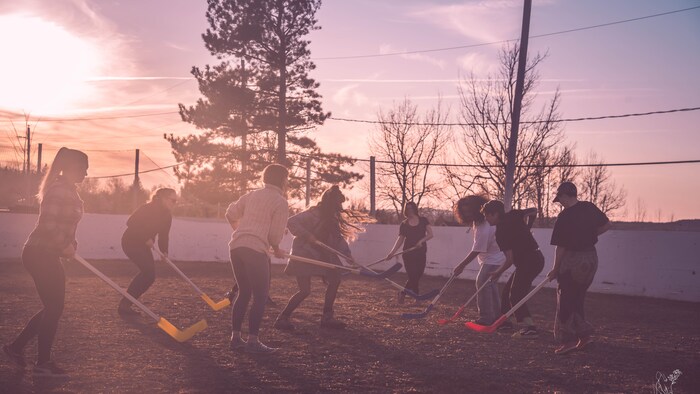 Un groupe de personnes avec des bâtons de hockey s'affrontent lors d'une partie de hockey bottine.