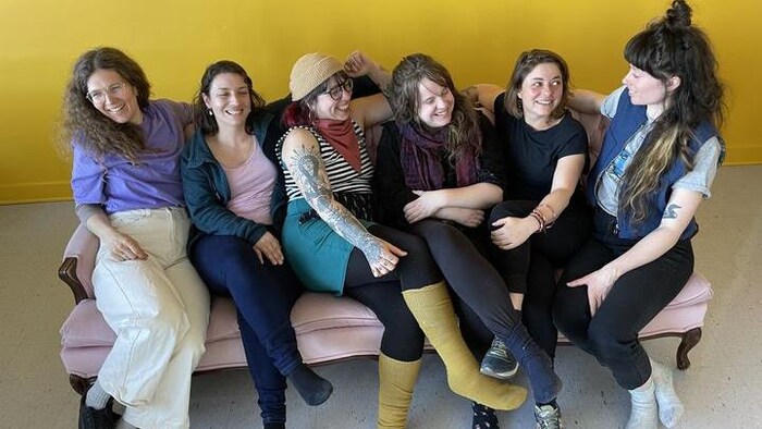 Six jeunes femmes souriantes assises sur un divan.