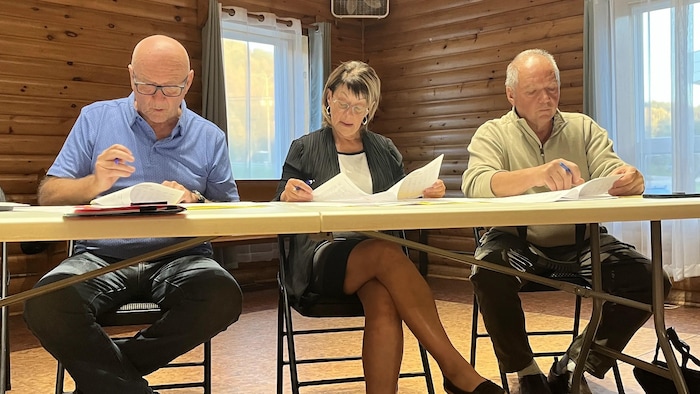 Trois personnes sont assises à une table.