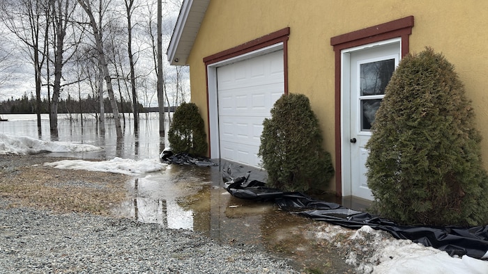 L'eau d'un lac à Rouyn-Noranda a monté jusqu'à la porte d'un garage. Une bâche a été déployée pour empêcher l'eau de rentrer.