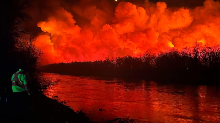Un premier répondant face à la rivière Carrot au Manitoba, près de The Pas. De l'autre côté de la rivière, de la fumée et un incendie.