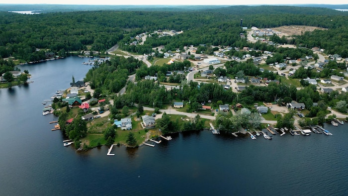 Vue aérienne de maisons bordant un lac. 