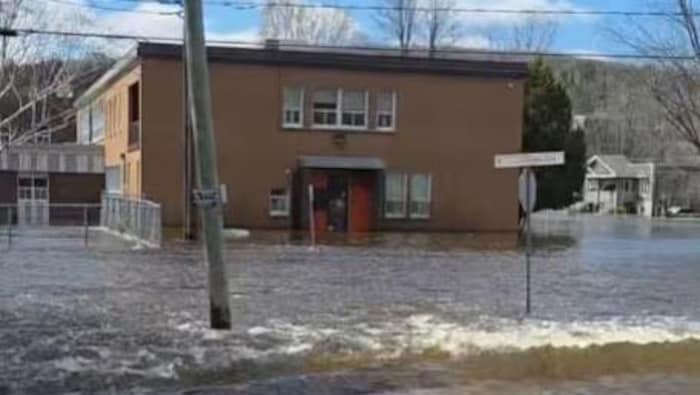Un école entourée par l'eau qui ruisselle le long des rues.