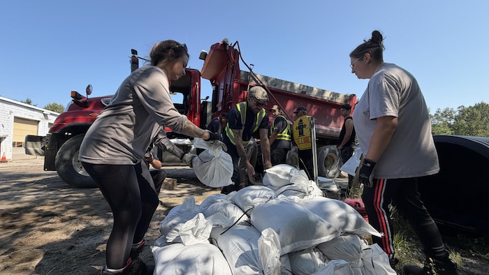 Des employés municipaux empilent des poches de sable.