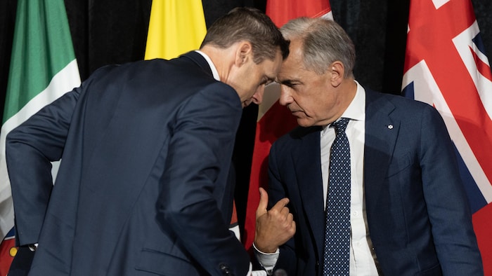 Rob Lantz incline la tête vers Mark Carney, qui lui adresse la parole, et l'angle de la photo donne l'impression que leurs deux crânes s'entrechoquent.