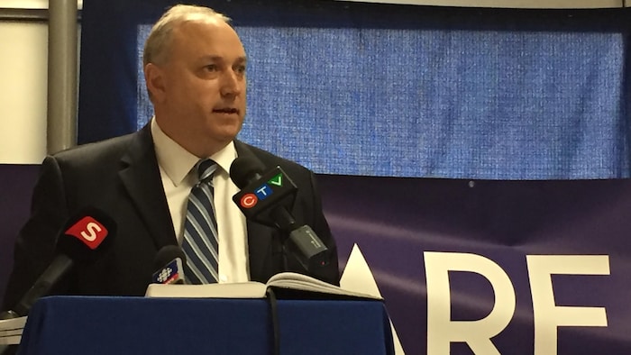 Le directeur général des Wolves de Sudbury, Rob Papineau derrière le lutrin.