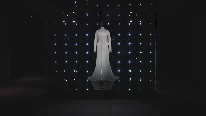 Une robe est exposée devant des lumières.
