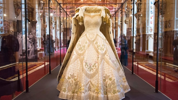 Une longue robe blanche est exposée dans une vitrine
