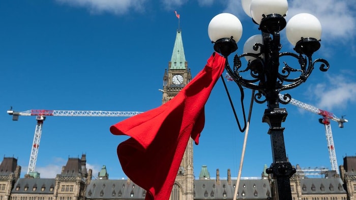 Une robe rouge flotte devant le parlement à Ottawa.
