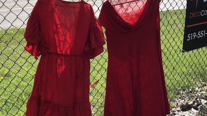 Des robes rouges accrochées sur une clôture.