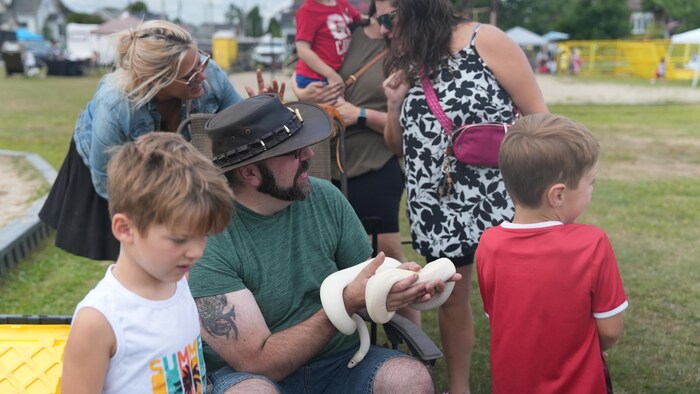 Un homme avec un serpent dans les mains.