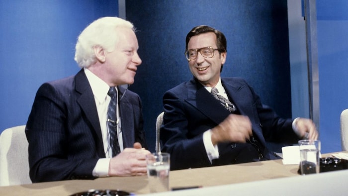 Dans un studio de télévision, Pierre Bourgault et Robert Bourassa discutent, assis à la même table.