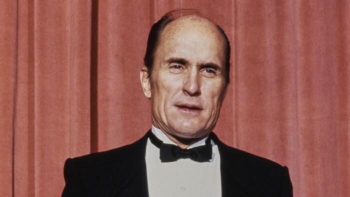 L'acteur pose devant un rideau rouge avec son Oscar.