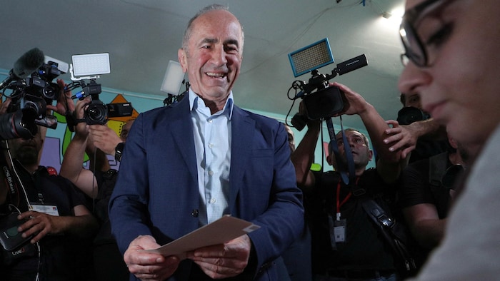 Robert Kocharyan, qui tient un bulletin de vote, est entouré de journalistes.