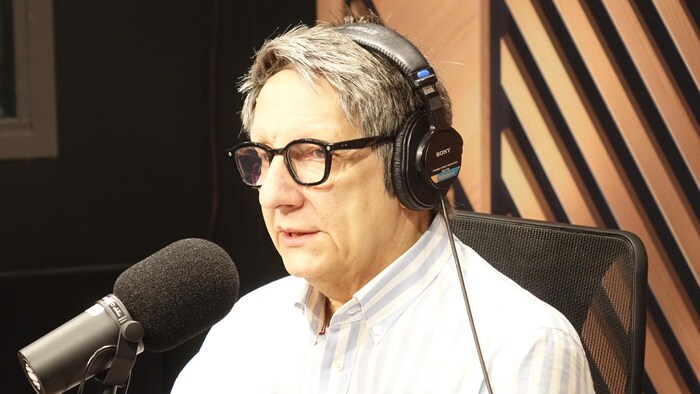 Un homme est assis dans un studio de radio.