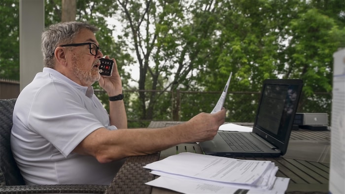 Robert L'Heureux au téléphone, papier à la main.