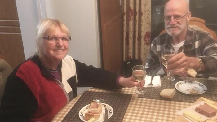 Un verre de vin à la main, du pâté sur la table
