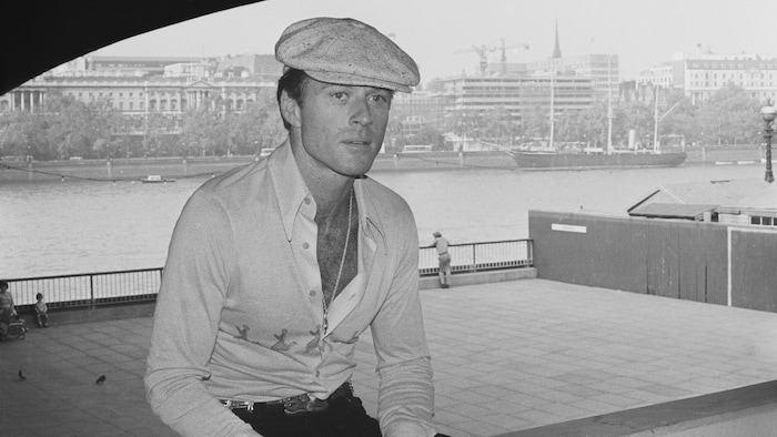 Robert Redford portant une casquette sous un pont.