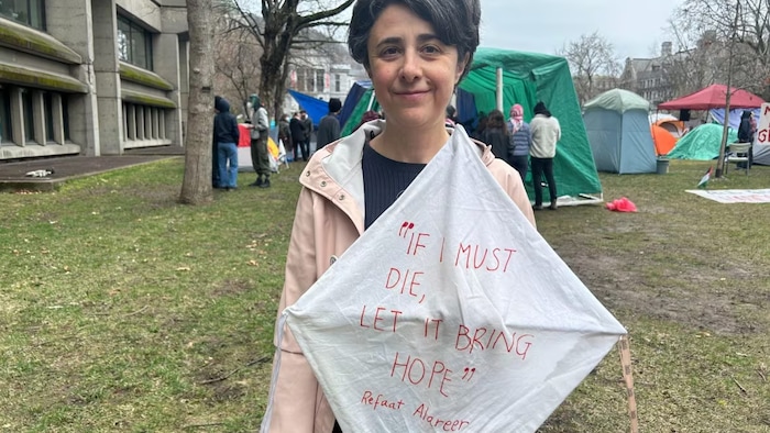 McGill Assistant Professor Roberta La Piana brought her kids to the encampment Sunday in solidarity with students protesting. She holds a handmade kite with a quote from Gazan poet Refaat Alareer, who was killed by an Israeli airstrike in December.