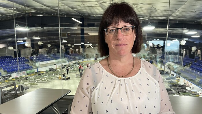 Une femme pose devant un aréna avec des lits.