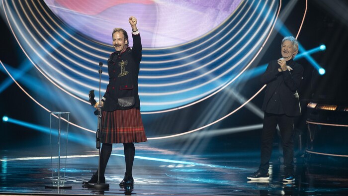 L'acteur lève un poing dans les airs en signe de victoire sur scène. 