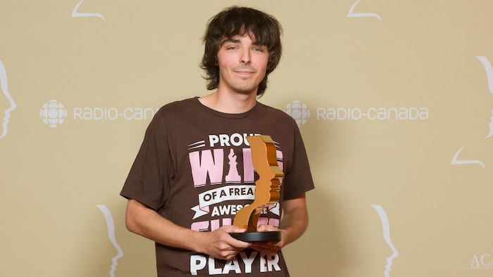 Robin L'Houmeau sourit légèrement à la caméra en tenant son trophée.
