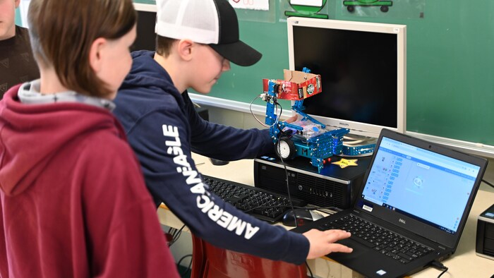 Des élèves dans une classe font de la programmation sur un ordinateur. 