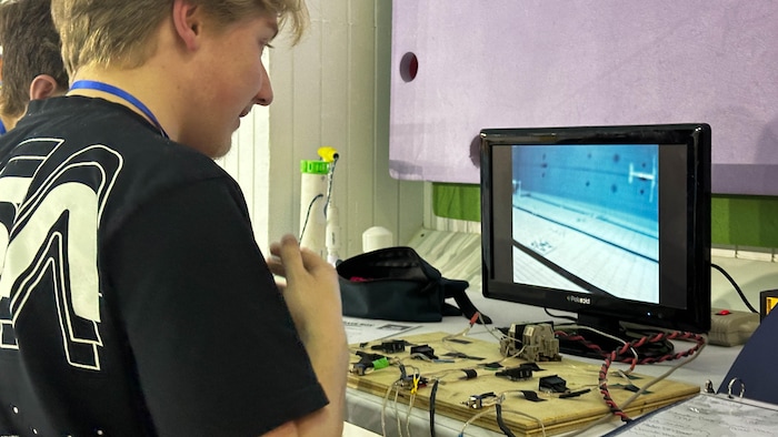 Deux adolescents manoeuvres leur robots depuis un écran.