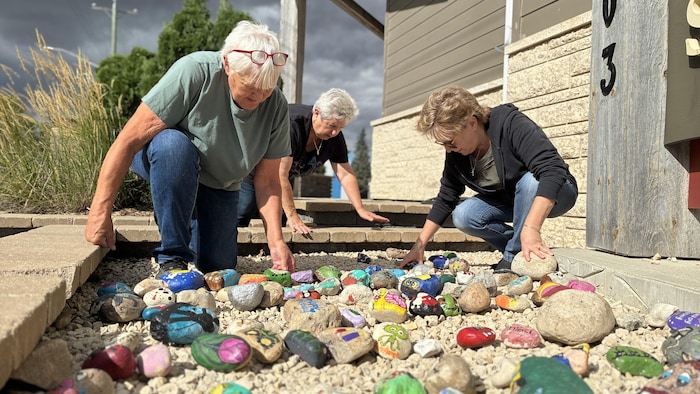 Trois femmes déposent des roches par terre.