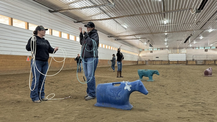 Ashley Watt parle à une femme dans un enclos d'entraînement pour la prise de veau au lasso.