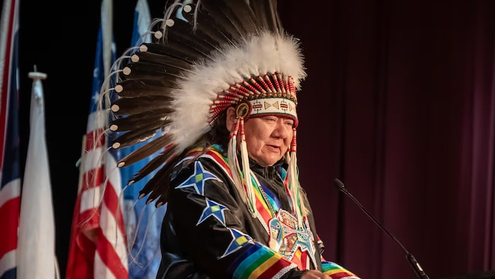 Rodger Redman, chef de la Première Nation Dakota de Standing Buffalo, devant un pupitre et s’adresse à l'audience. 
