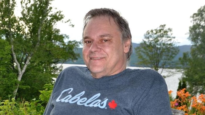 Un homme d'une cinquantaine d'années souriant.