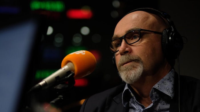 Roger Ferland dans un studio de radio derrière un micro.