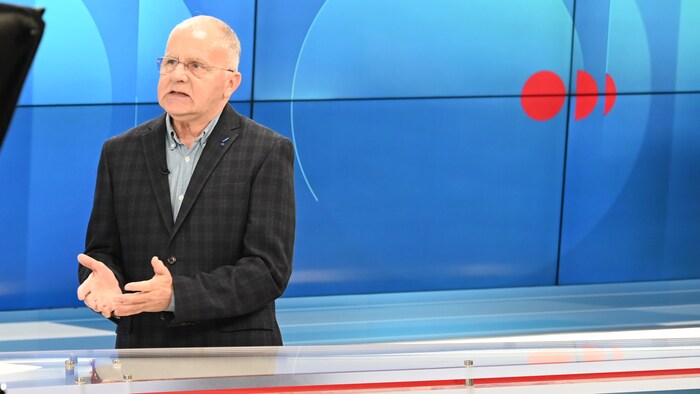 Un homme répond aux questions d'un journaliste.
