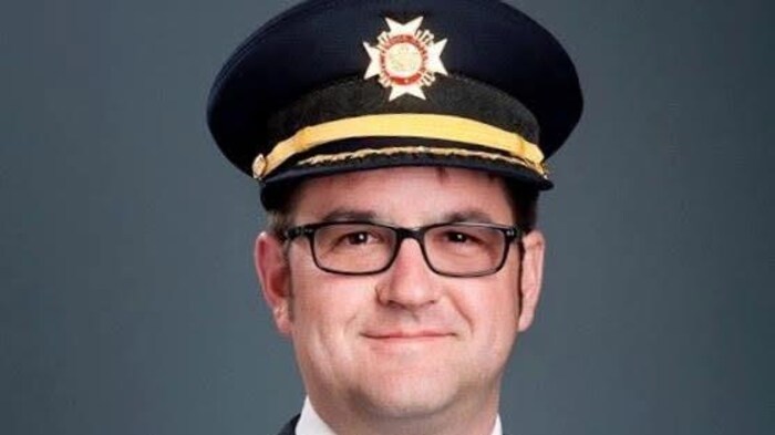 Un pompier en uniforme sourit à la caméra.